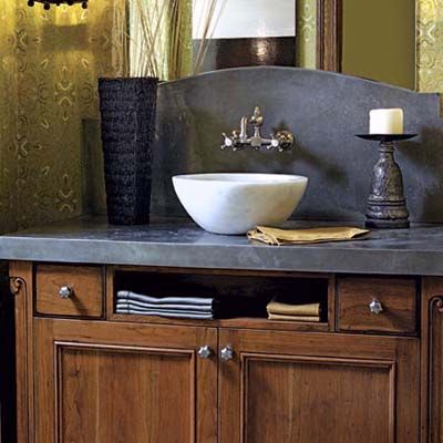 A half bathroom vanity with wooden cabinets, a slate countertop, and a white vessel sink.