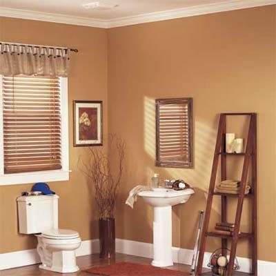 A cozy half bath with warm beige walls features a white pedestal sink, a matching toilet, and a wooden ladder shelf.