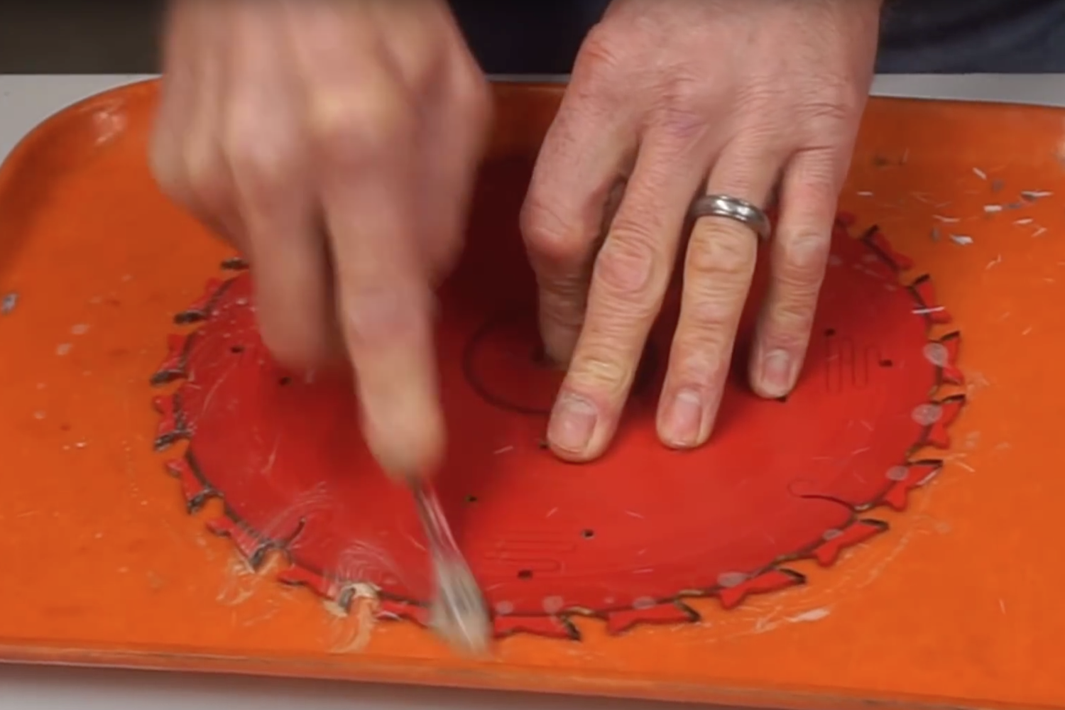 A person cleaning saw blades on a table.