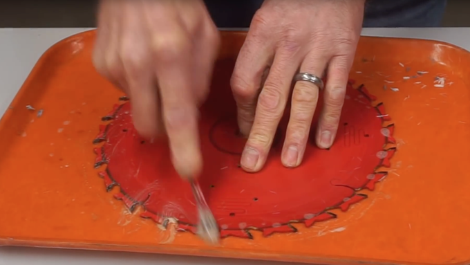 A person cleaning saw blades on a table.