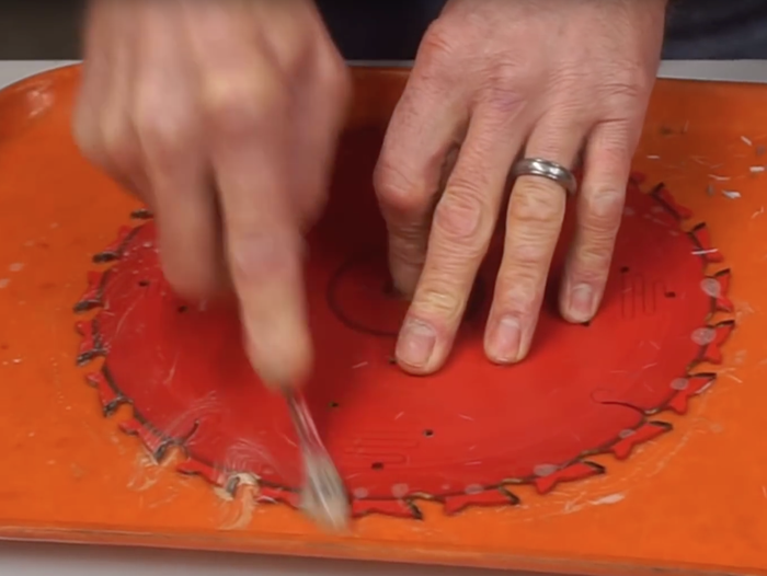 A person cleaning saw blades on a table.