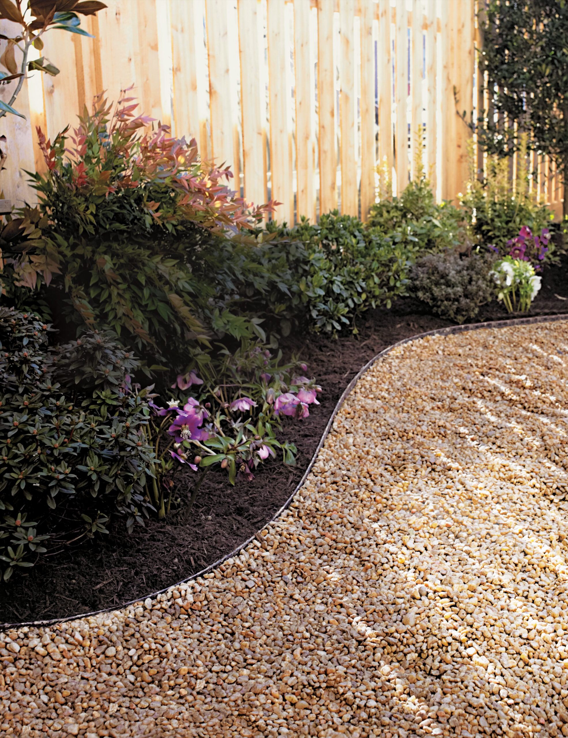 A gravel pathway alongside a home garden.