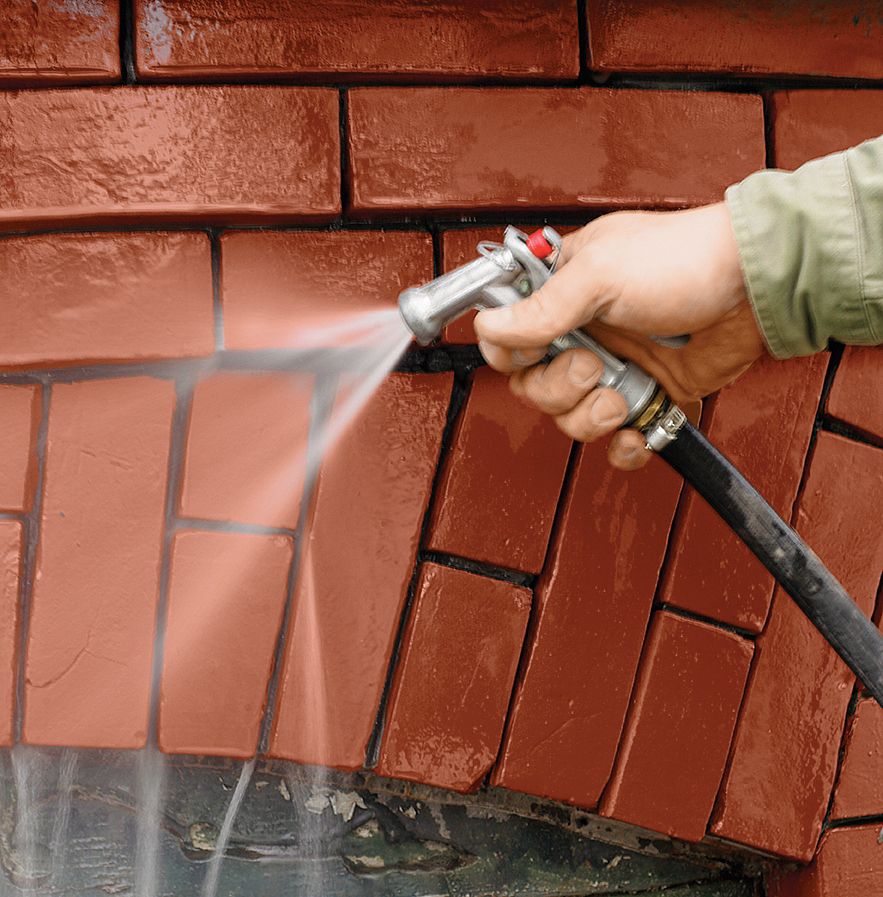 A person wets the brickwork with a hose before adding the new mortar.