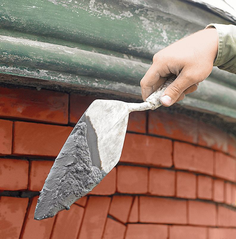 A pointing trowel with mortar on it.