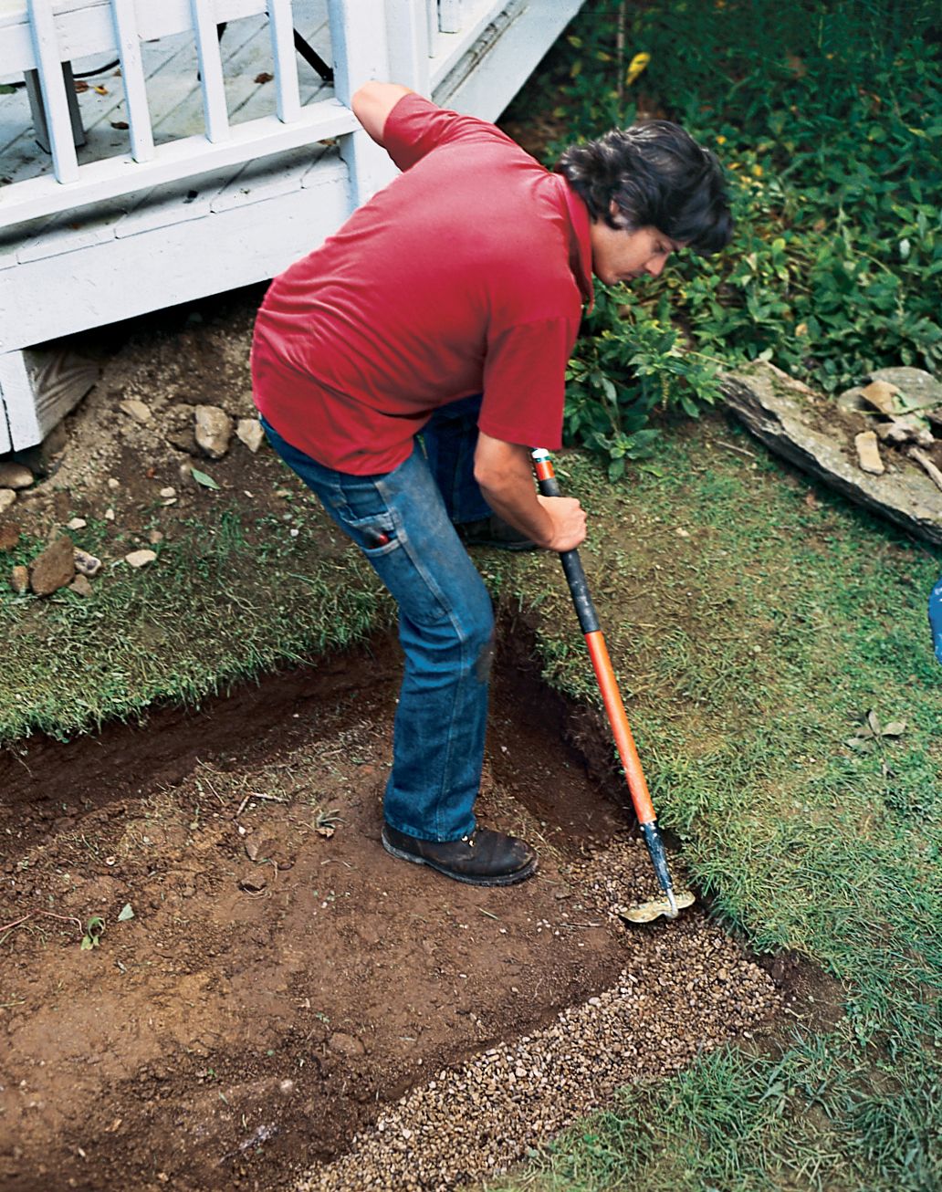 A man digs trenches for the walls of his raised planting bed.