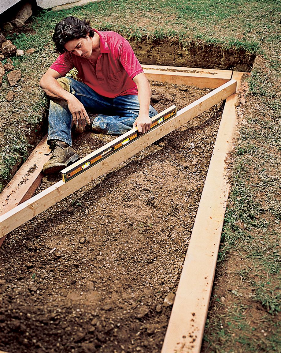 A man sets the first course of timbers.