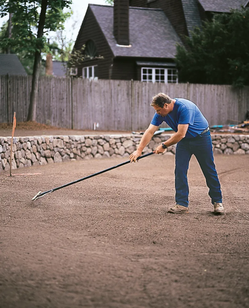Rodger Cook rakes the soil's surface to prepare it for grass sod.