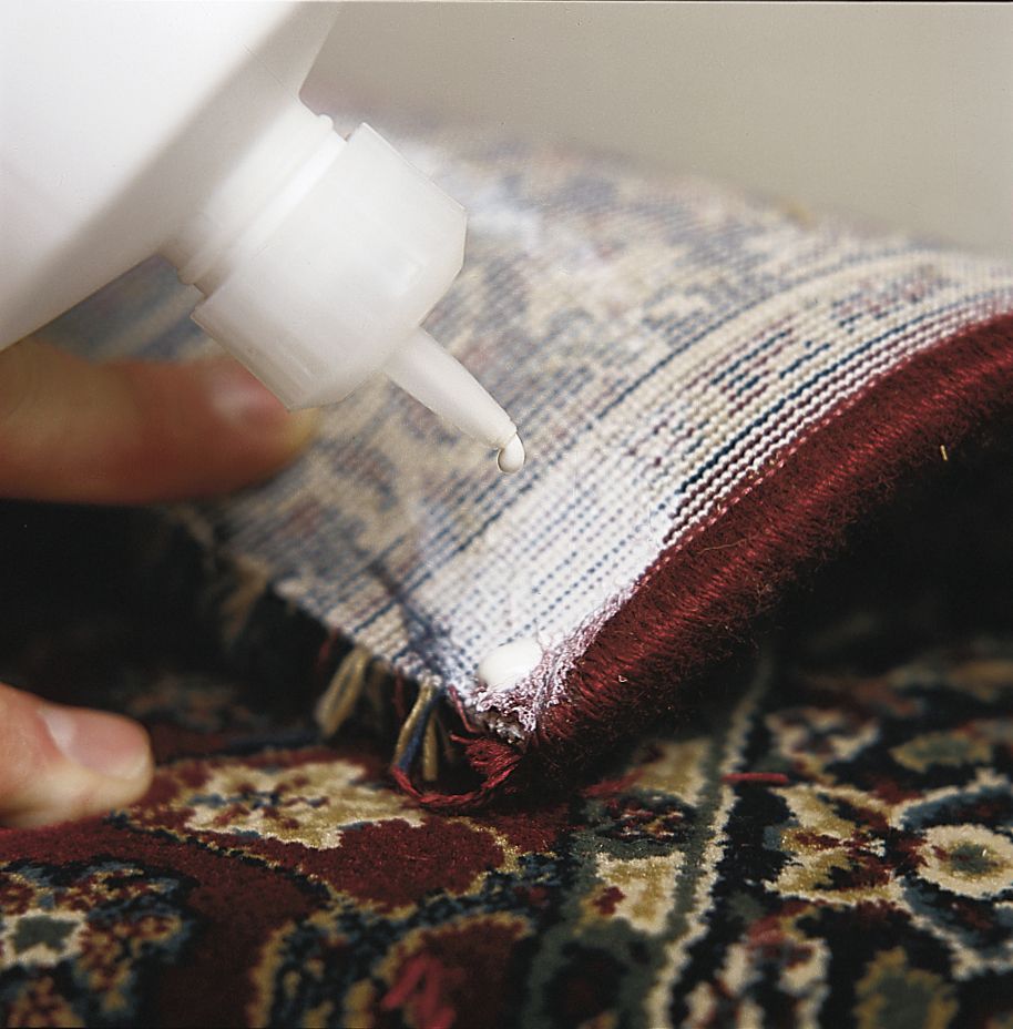 A person puts glue on the back of a carpet stair runner.