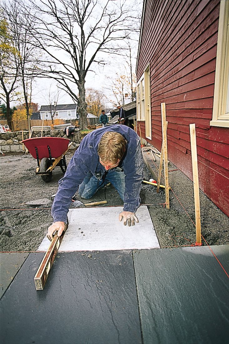 A man smoothing stone for a home patio.