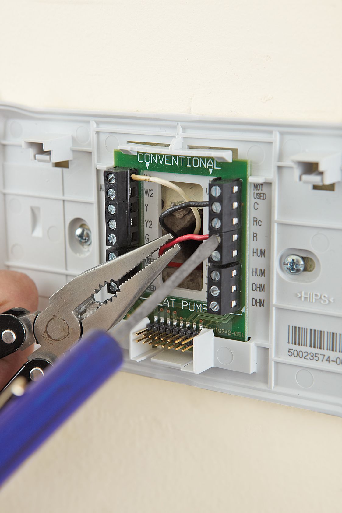 Photo of a person connecting the wires on a progammable thermostat.