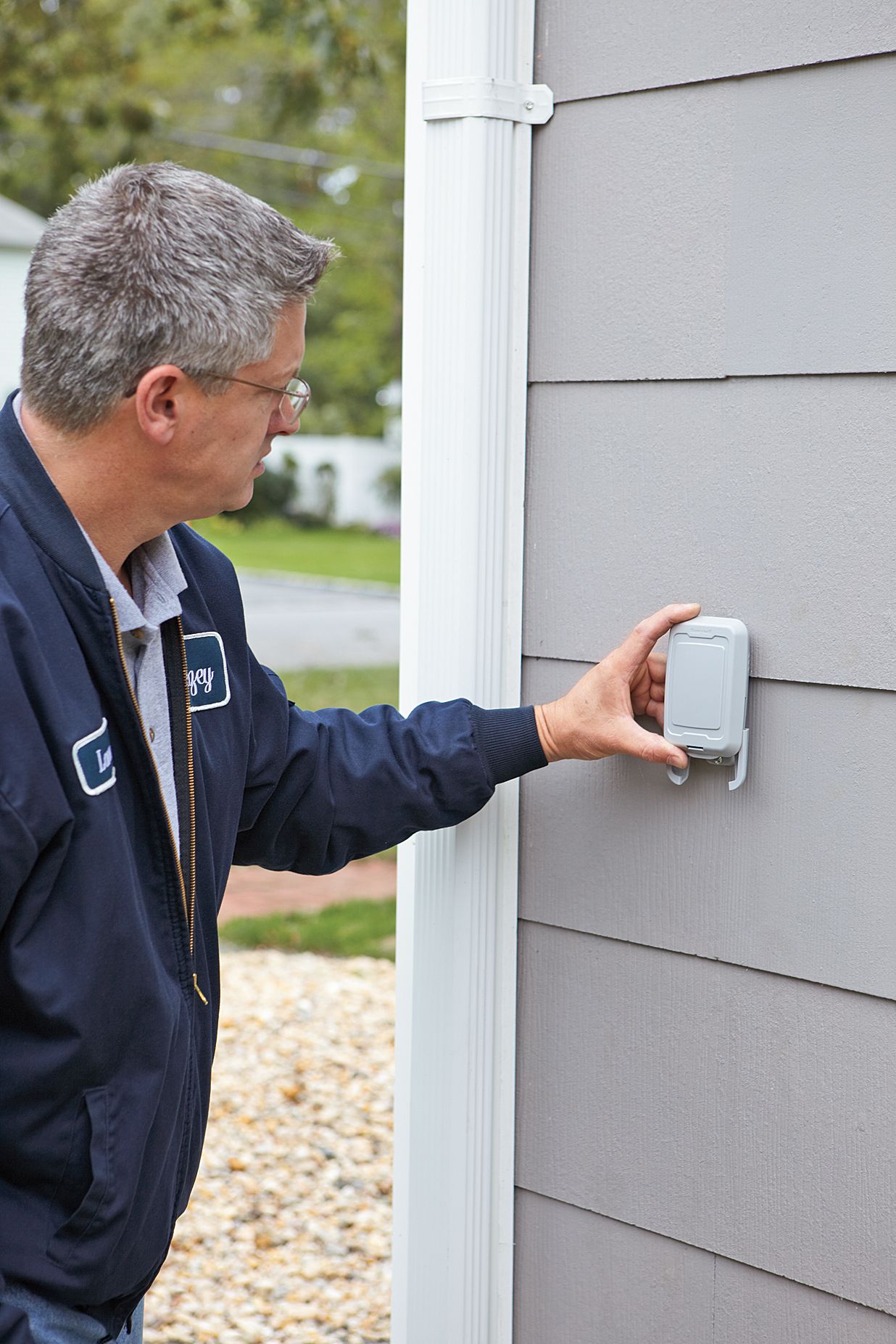 Photo of a person mounting the outdoor sensor for a programmable thermostat.