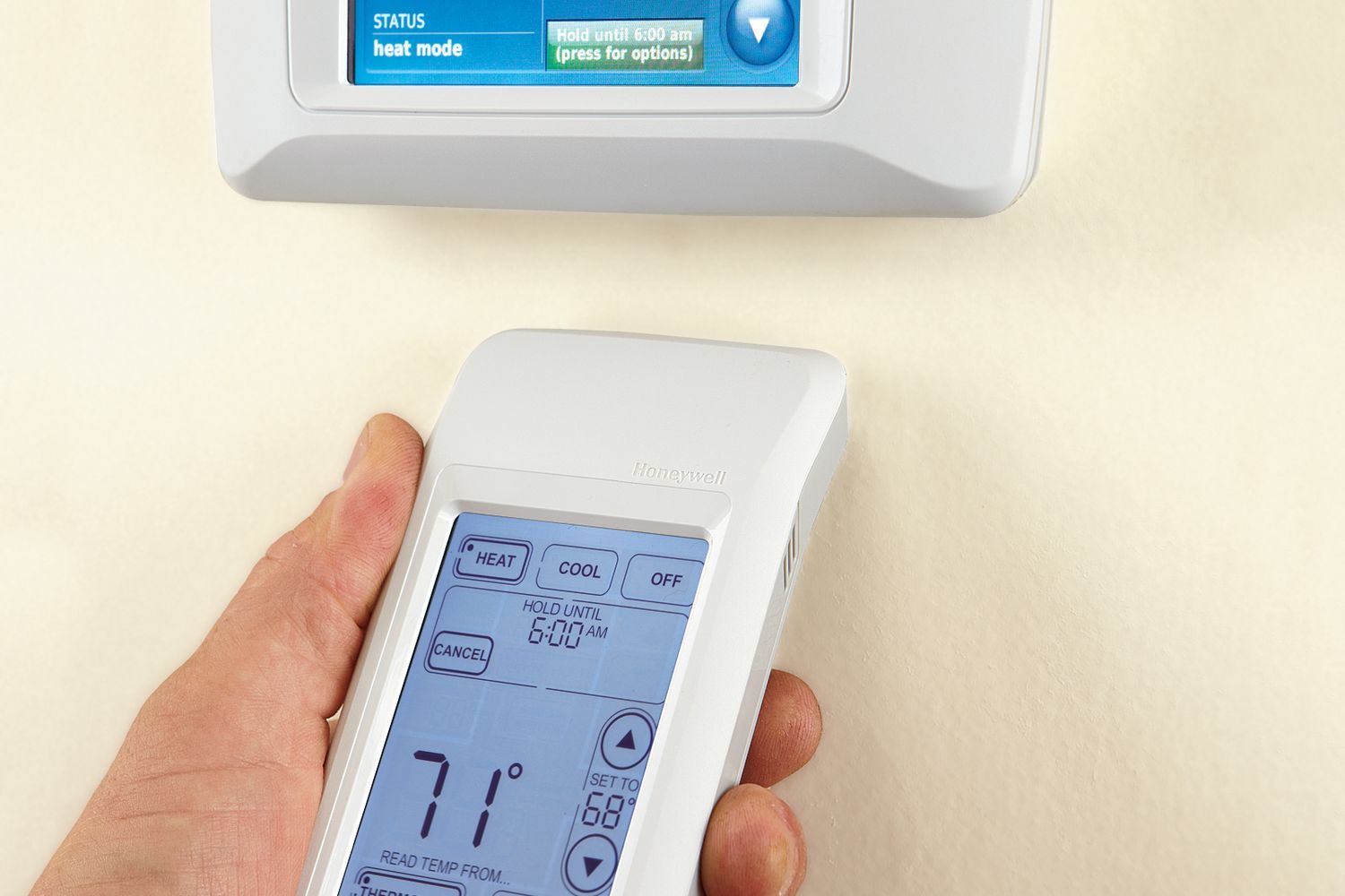 Photo of a person adjusting their programmable thermostat with a remote.