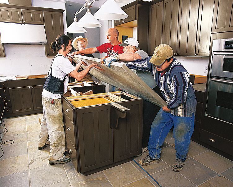 A group of people placing the top onto a kitchen island.