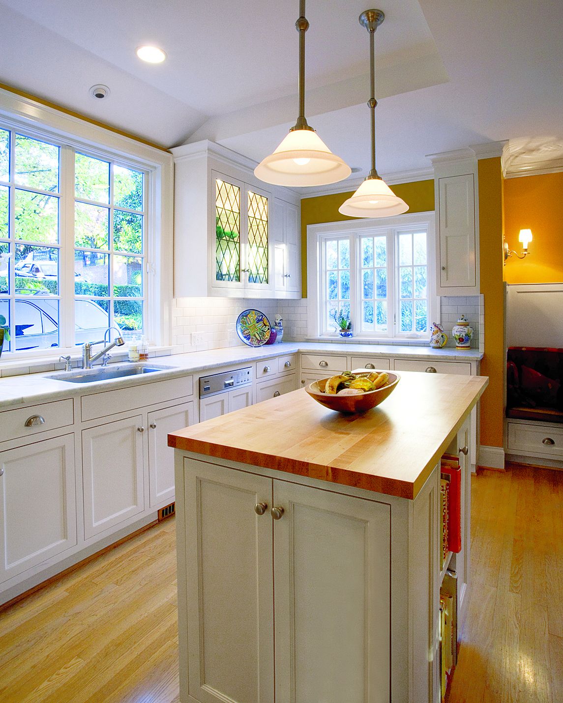 A small kitchen with stainless steel appliances, white cabinets, and a  natural light colored wood counter top Stock Photo - Alamy