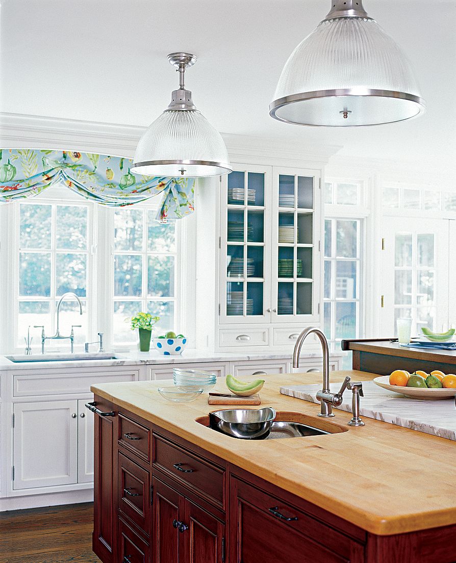 A kitchen island with chandeliers hanging over it.