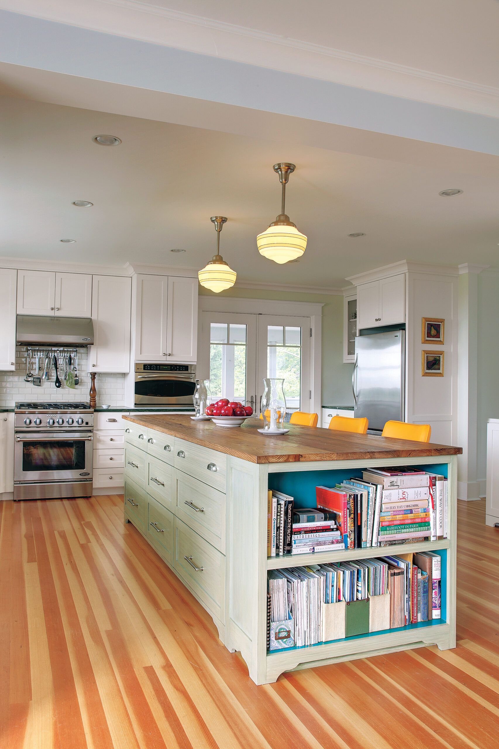 A kitchen island with a wood top and bookshelf.