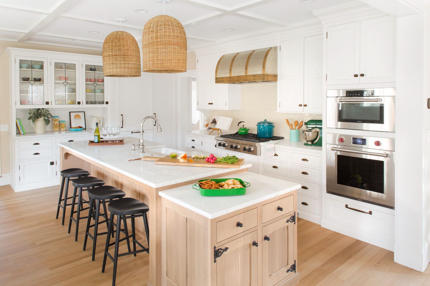 A kitchen island with a white countertop and black stools.