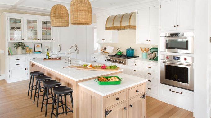 A kitchen island with a white countertop and black stools.