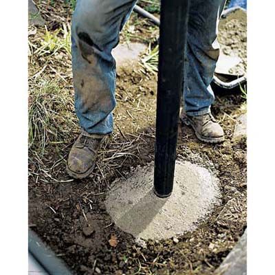 A lamppost being placed in wet cement.