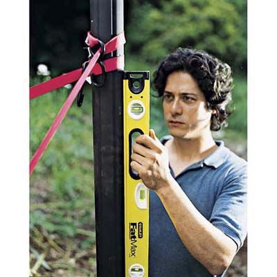 A leveler being used to check that a lamppost is plumb in the ground.