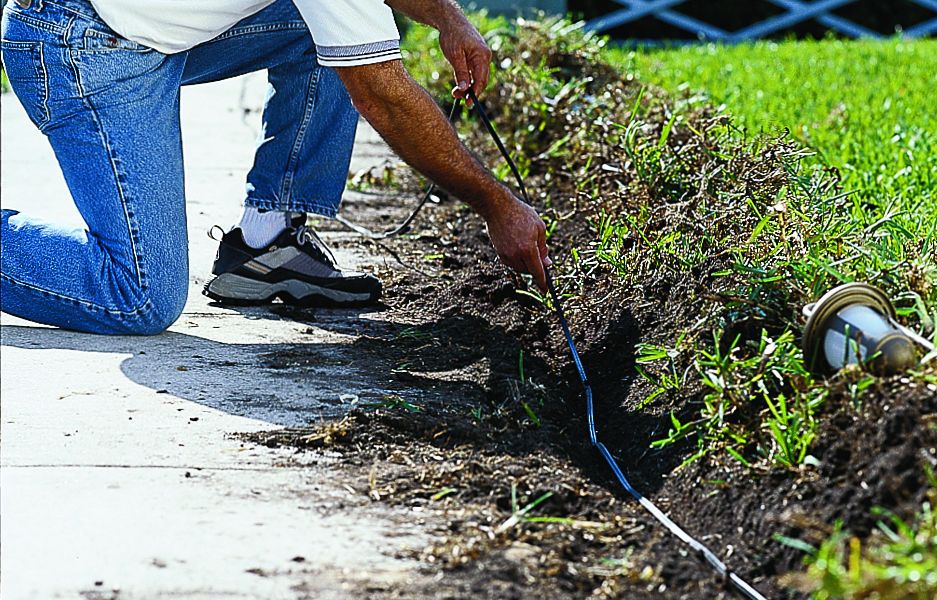 A man buries cables for landscaping lights.