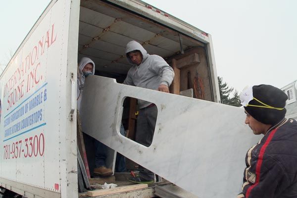 Three men unload new countertops from a truck to install for the budget-friendly kitchen makeover.