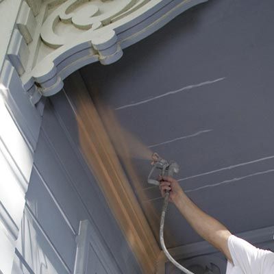 using a paint sprayer to paint hard to reach areas of the exterior of a home