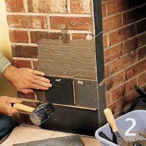 A mallet being used to set cardboard strips over the brick of a fireplace.