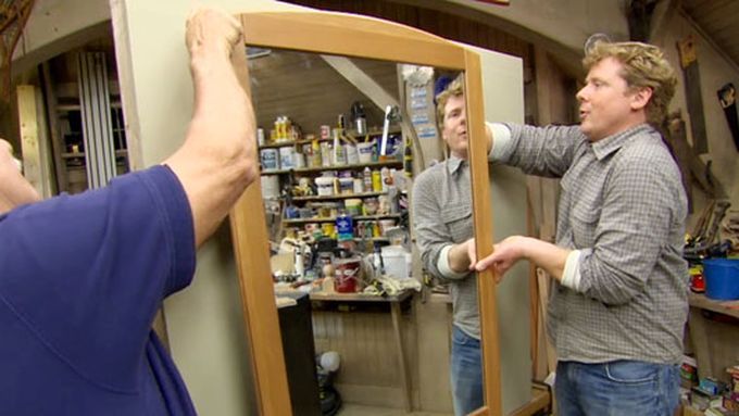 2 men installing a hanging mirror on a wall.