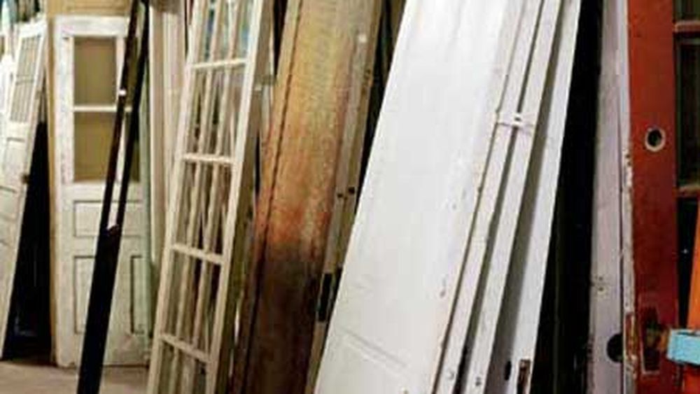 Several salvaged doors leaning against a wall.