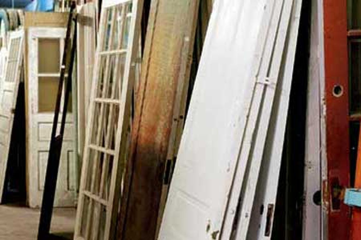Several salvaged doors leaning against a wall.