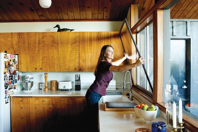 a woman installing a window in a kitchen