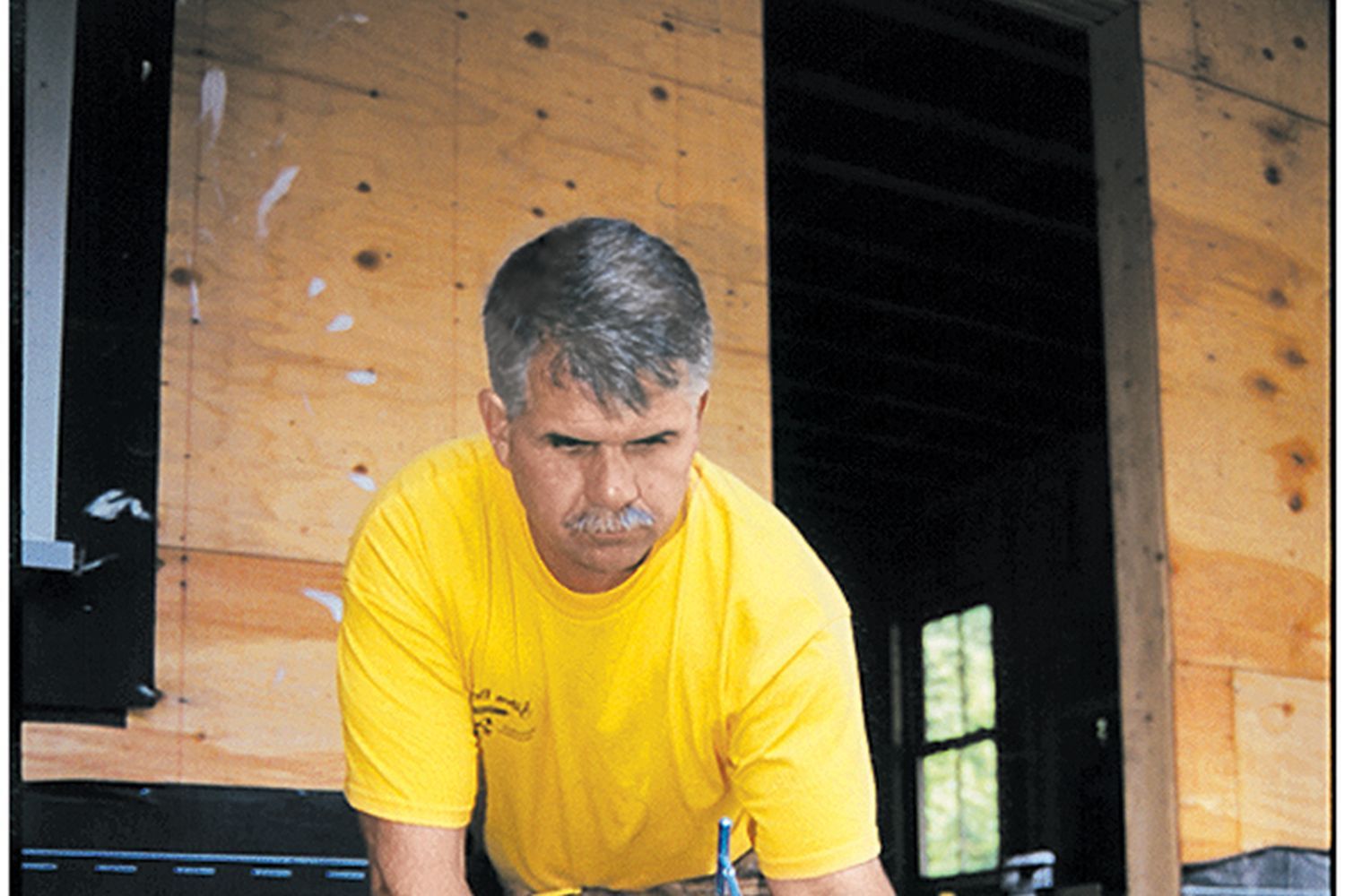 A man inspecting a deck and applying an adhesive to it.