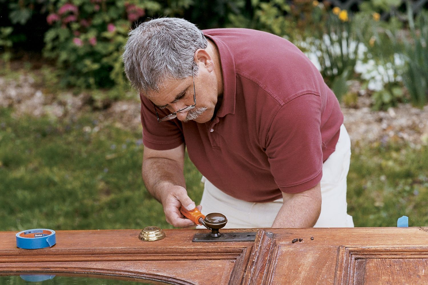A man refinishes an old, worn door to make it look new again.
