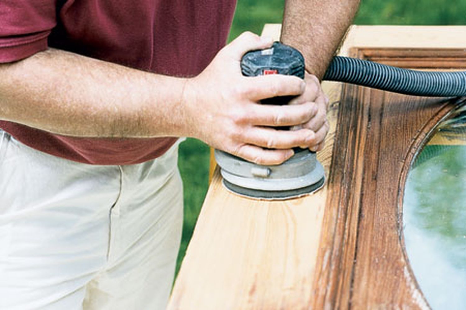 A person sands the finish off of a wooden door with the help of chemical stripper.