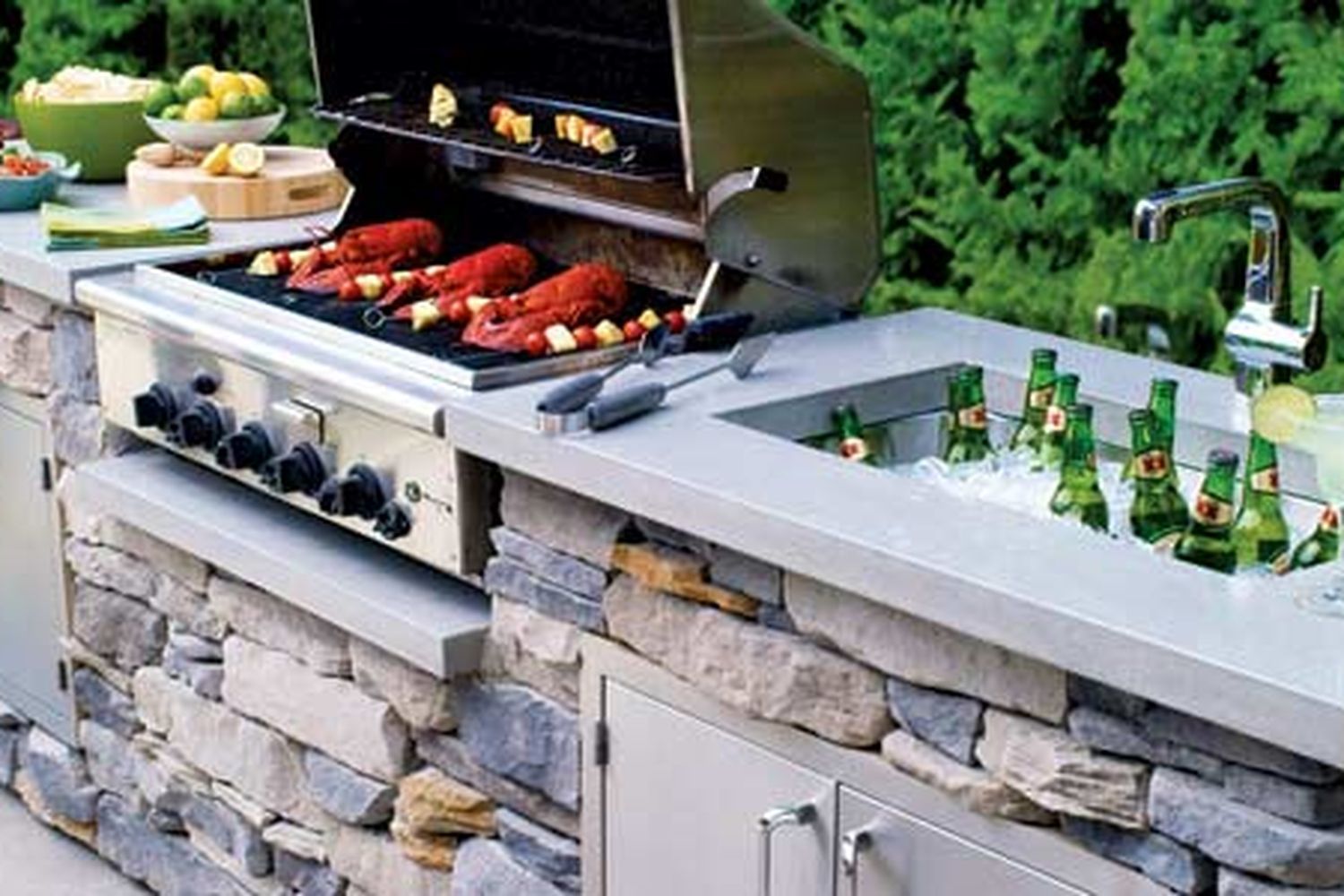 Outdoor kitchen with a grill, sink, and fridge.