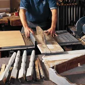 A man cutting through the crack in a disassembled table with a chain saw.