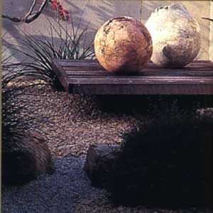 A gravel and stone path with garden artwork nearby.