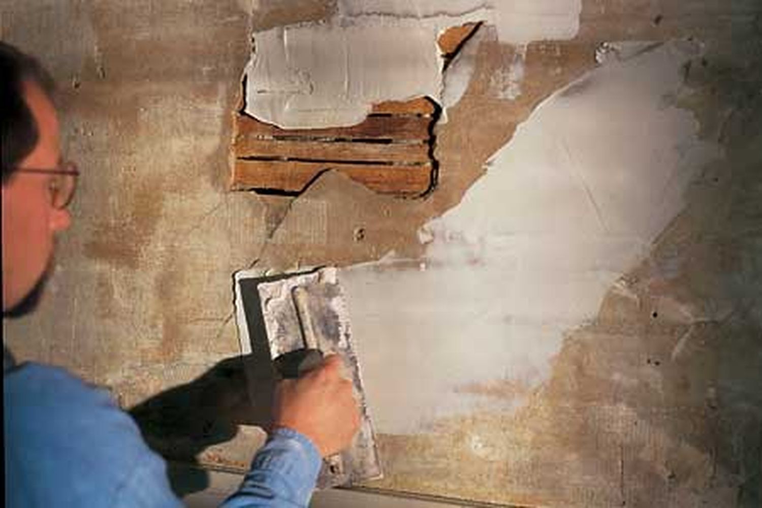 A man applying plaster to a wall.
