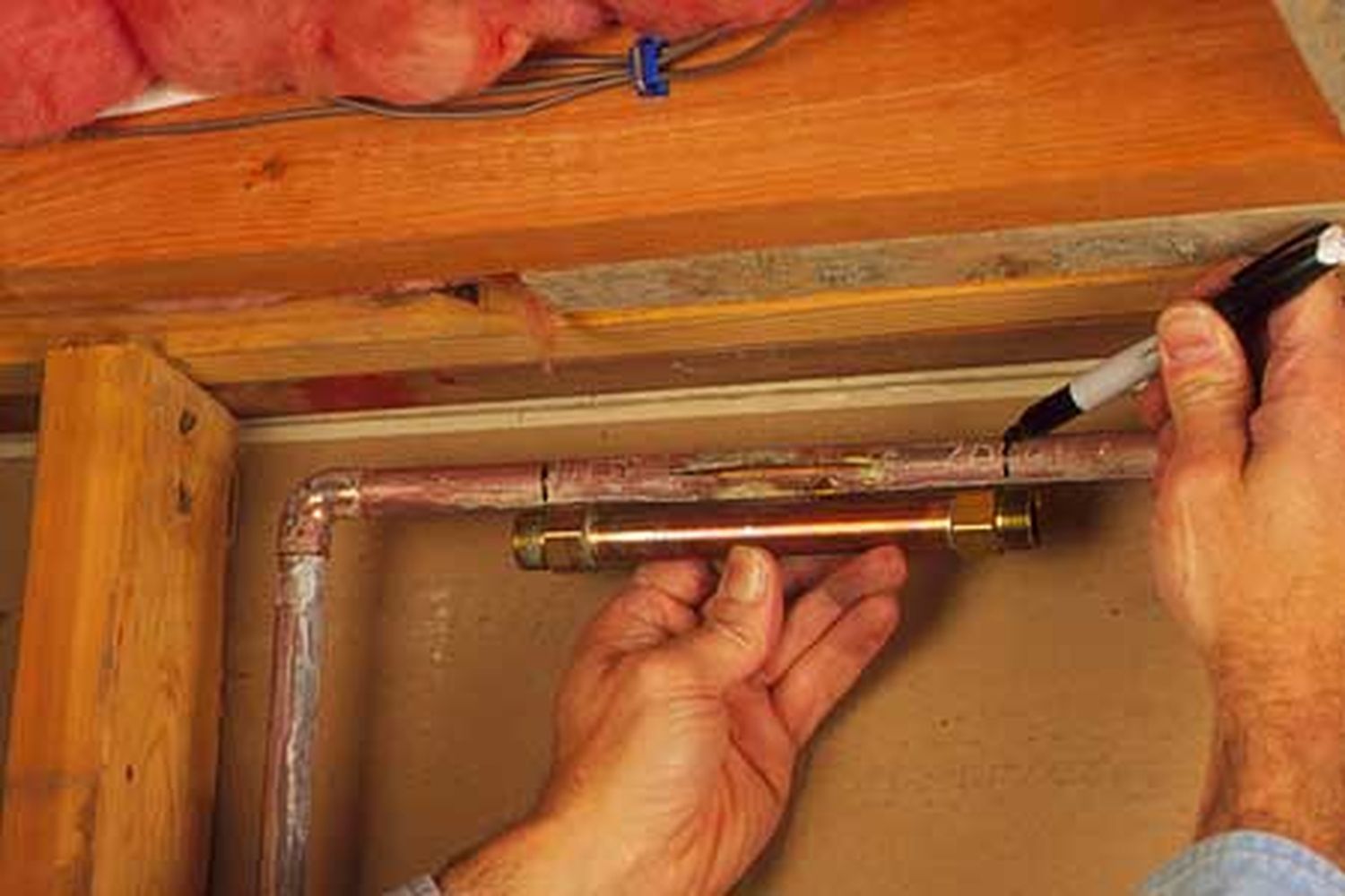 A man marking a damaged pipe before placing a repair coupling.