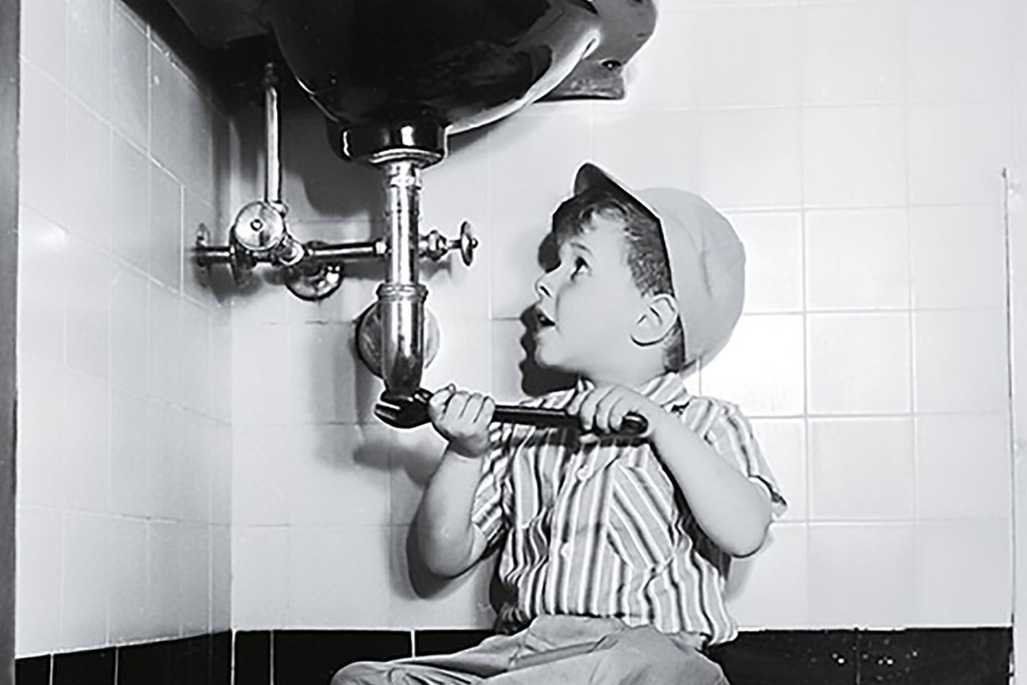 a little kid is trying to fix the pipes under a sink