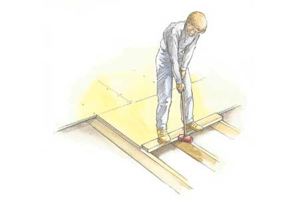 Drawing of a man using a mallet to install tongue-and-groove plywood.