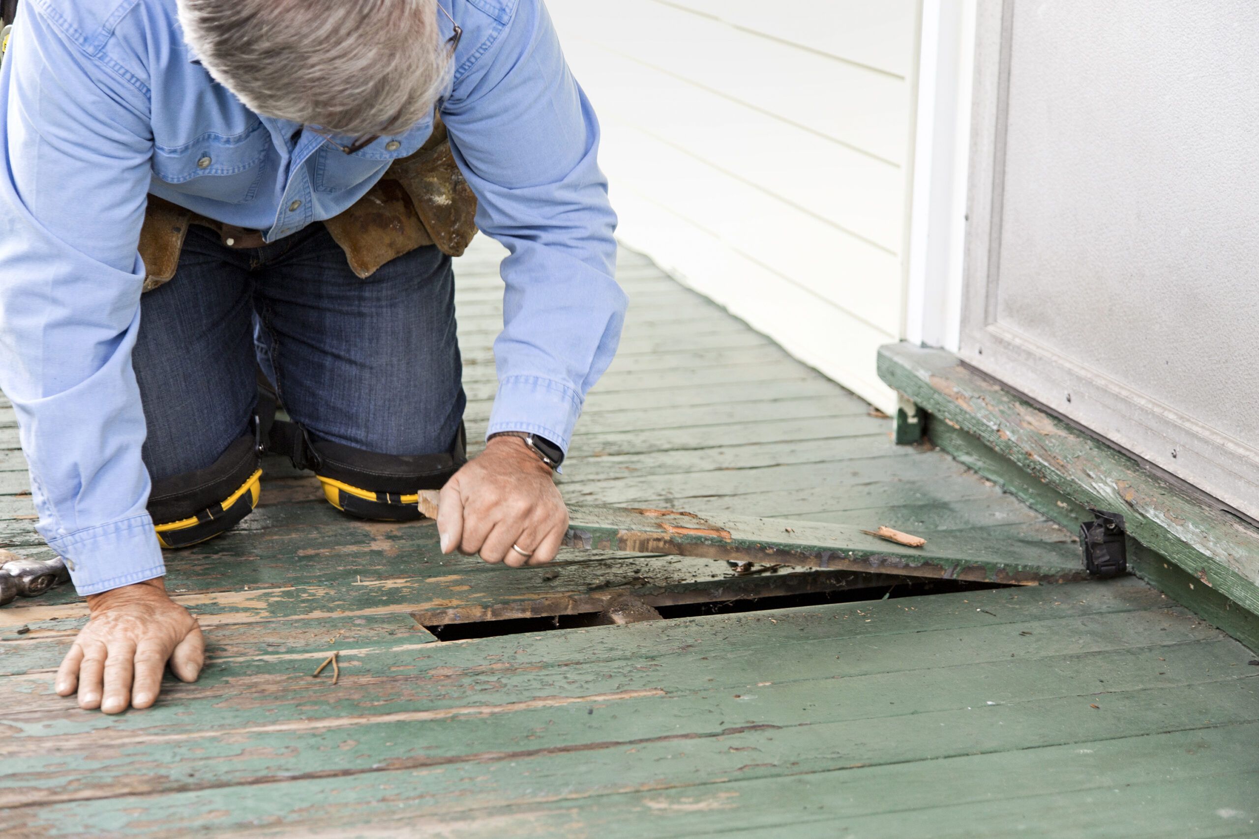 pulling up a damaged porch board after removing the nails