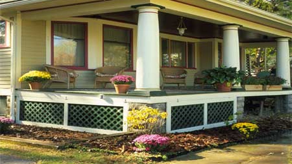 A home with a porch with a wooden lattice beneath it.