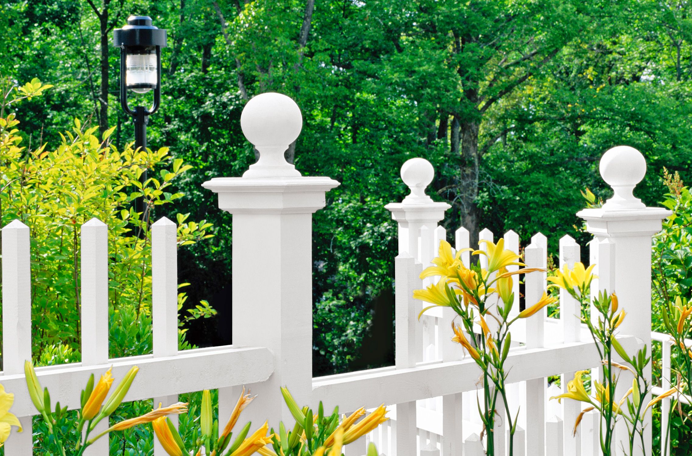 A picket fence with a ball accenting the larger posts.