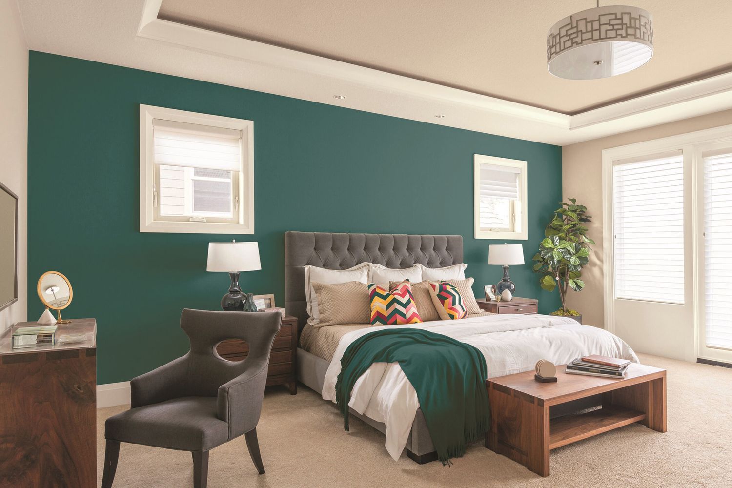 A bedroom with a green accent wall behind the bed.