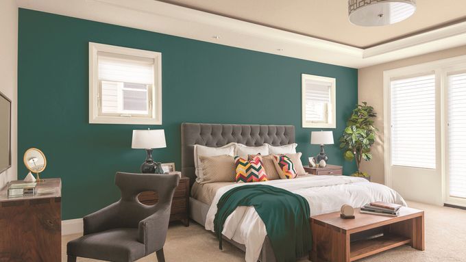 A bedroom with a green accent wall behind the bed.