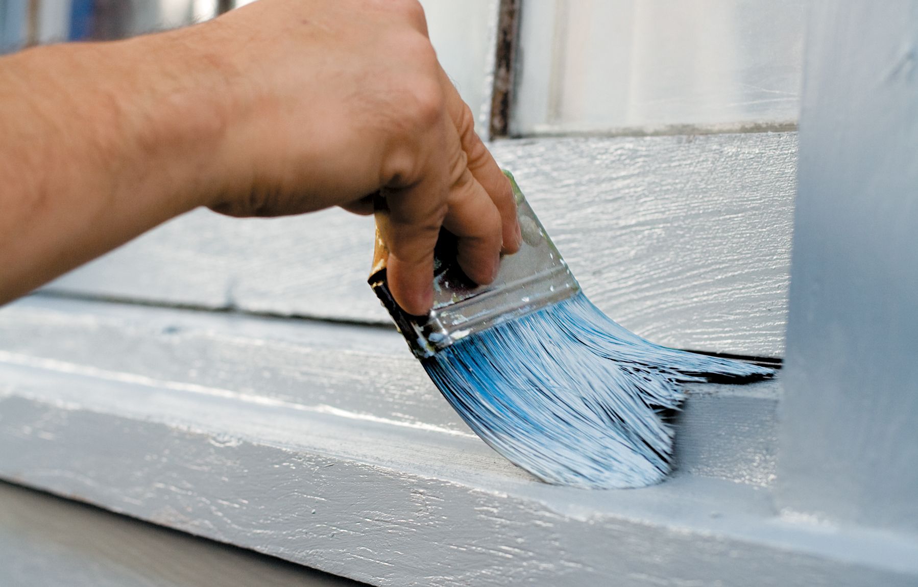 using a paintbrush to paint a windowsill