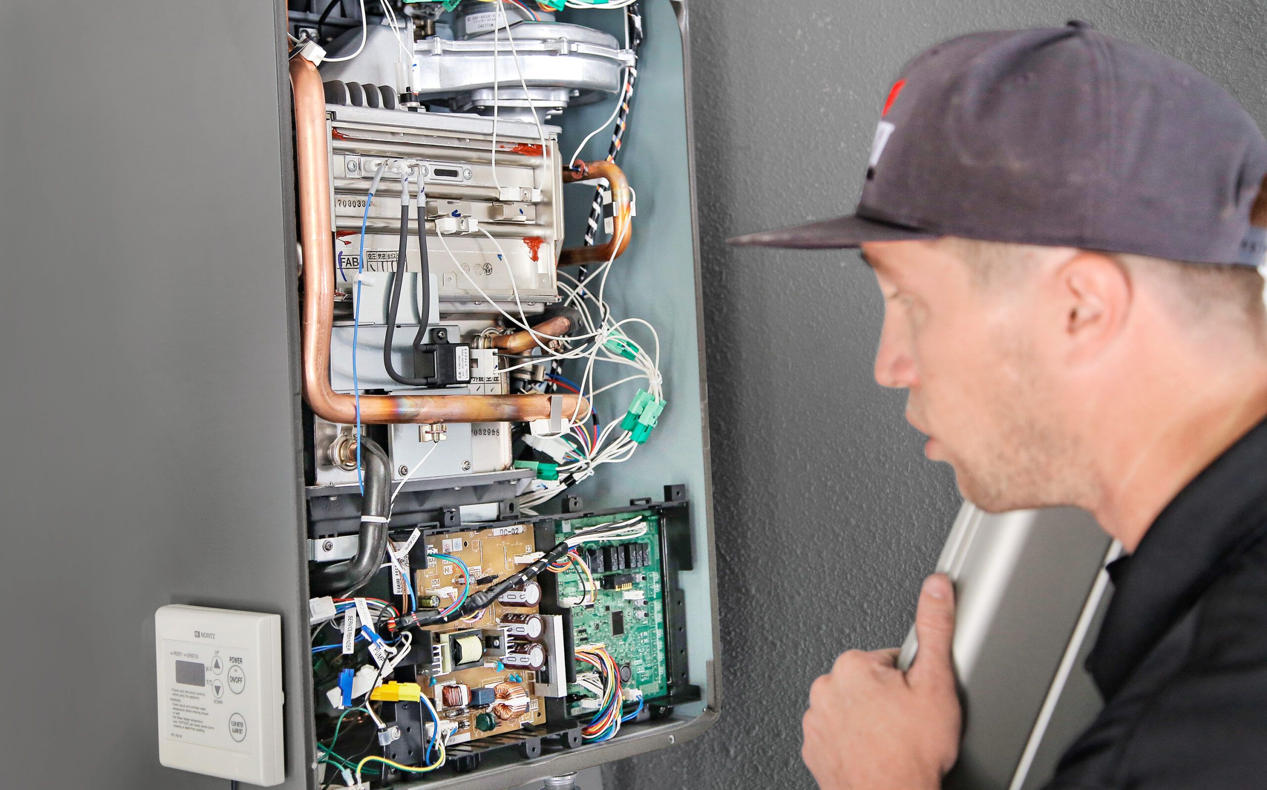 A man looks at the innerworkings of a tankless water heater