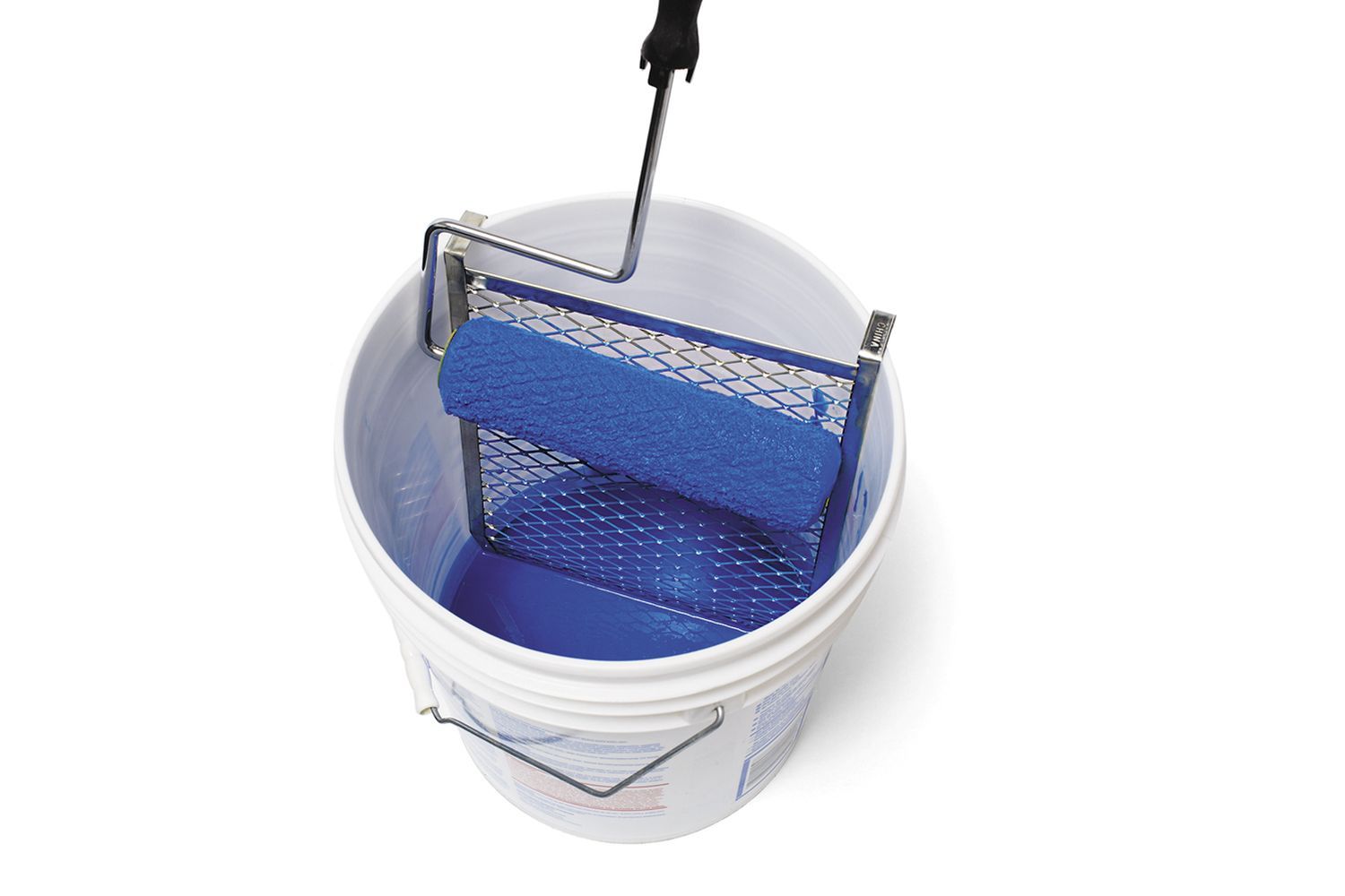 A paint roller is seen resting on a metal grid inside a white bucket, filled with blue paint.